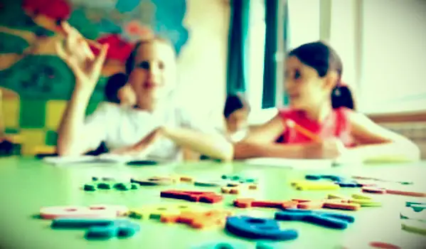 Enfants avec alphabet de plaque de jouet en bois en classe