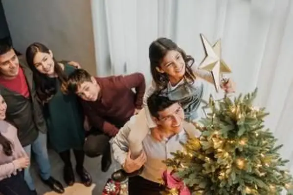 menina colocando estrela na árvore de natal