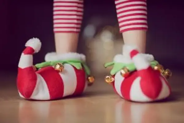 Criança com chinelos de Natal com sinos
