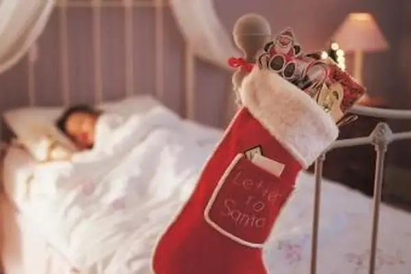 ベッドのノブにぶら下がっているクリスマスの靴下とベッドで寝ている子供