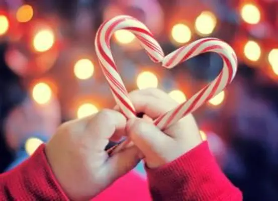 Kind hält Weihnachtssüßigkeit mit Herzform