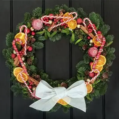 Weihnachtskranz an der Tür mit Zuckerstangen und Obst