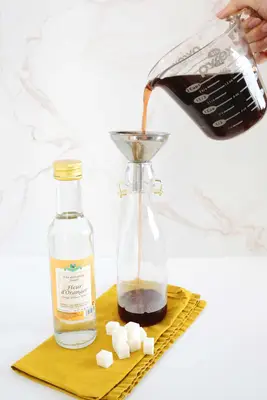 pouring homemade grenadine into a bottle