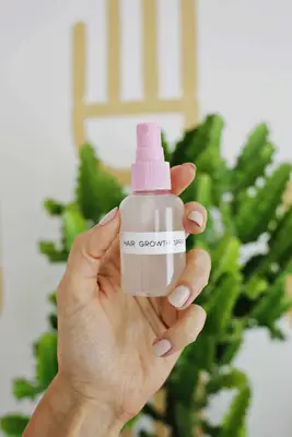 someone holding upa spray bottle labeled hair growth spray