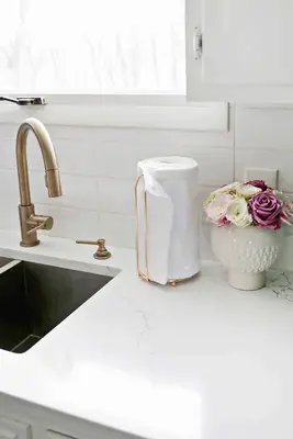 unpaper towels on towl holder next to sink and vase of flowers