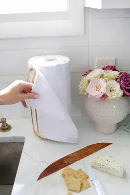 unpaper towels on towl holders next to vase of flowers and plate of crackers and cheese