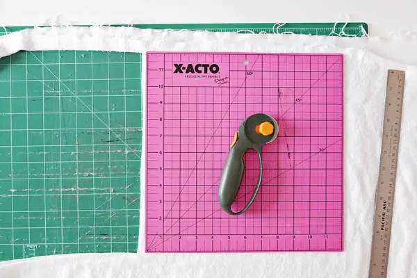 cotton fabric with pink cutting mat, ruler, and fabric cutter on top