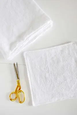 several pieces of cotton fabric with gold scissors laying next to it