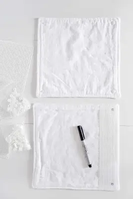 2 squares of cotton fabric, one with mash cover and sharpie on top