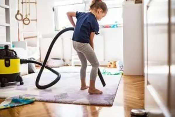 Ragazza che passa l'aspirapolvere sul tappeto