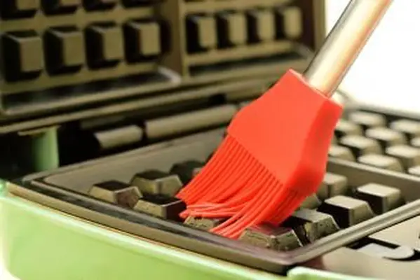 usando un cepillo de silicona para limpiar la plancha para gofres