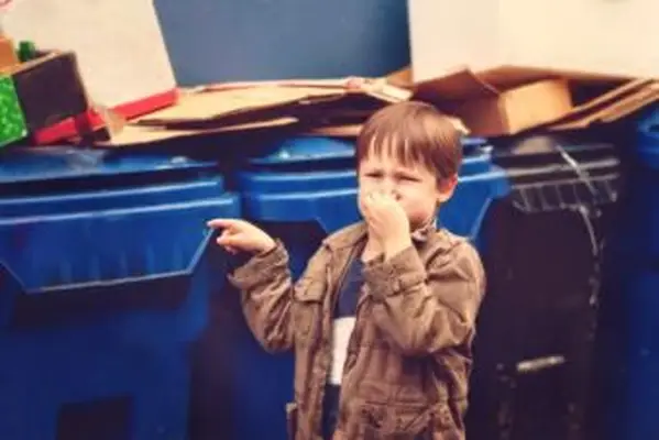 냄새 나는 쓰레기통 옆에 서있는 소년