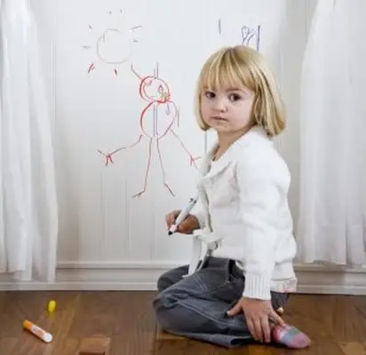 Niño dibujando en la pared con marcadores