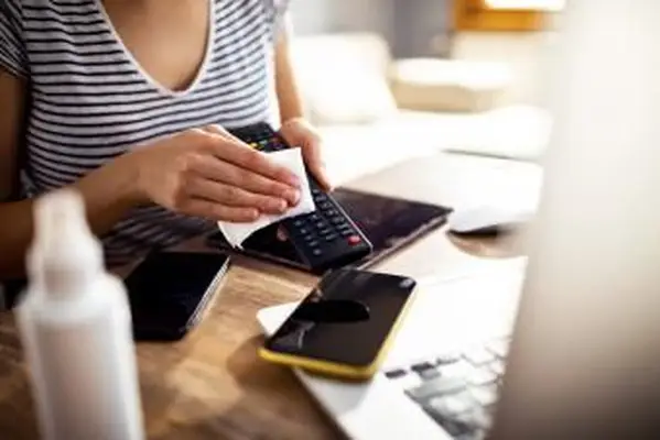 Mujer limpiando y desinfectando el mando a distancia del televisor.