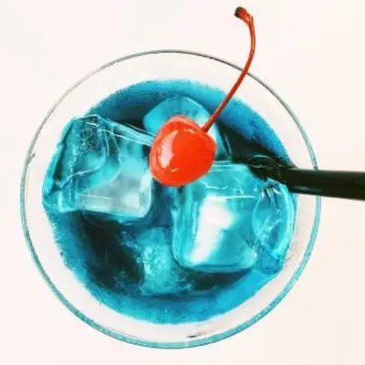 Cherry In Blue Cocktail Against White Background