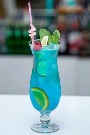 Cocktail Blue Lagoon avec une tranche de citron vert et menthe