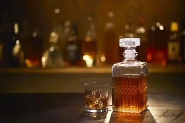 Whisky on the Rocks w Tumblerze na barze z butelkami w tle