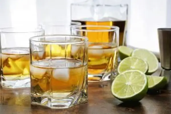 Koktajl whisky z plastrami limonki, lodem i mieszadełkiem w eleganckiej oprawie