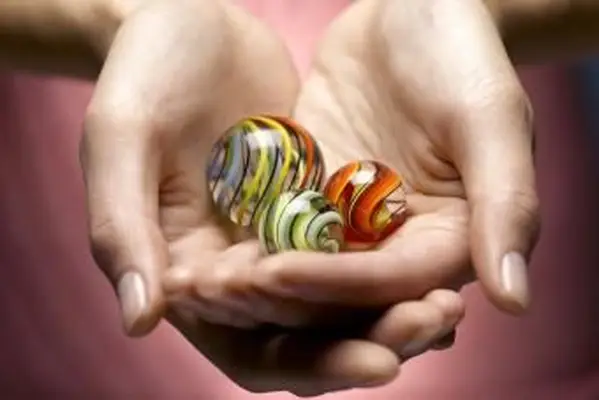 Giovane donna che tiene biglie di vetro nelle mani a coppa