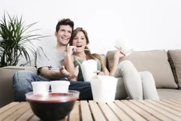 Casal curtindo comida para viagem enquanto assiste TV