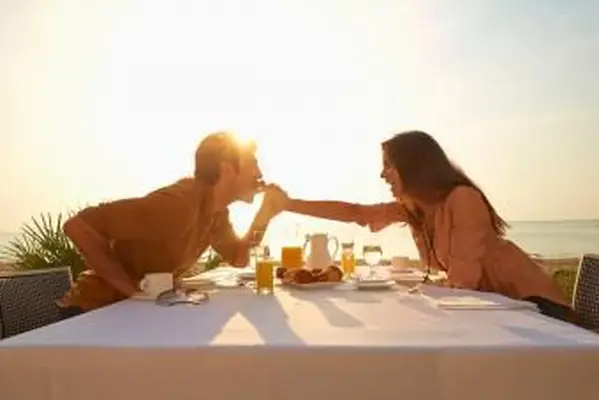 Mulher alimentando homem no jantar ao pôr do sol ao ar livre