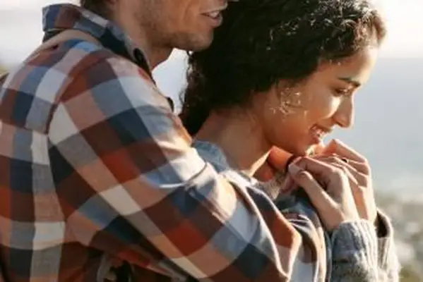 Souriante jeune femme dans les bras de son petit ami à l'extérieur