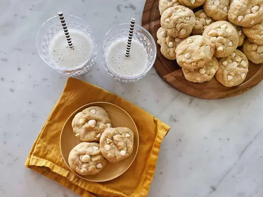 cookies on plate by glasses of milk