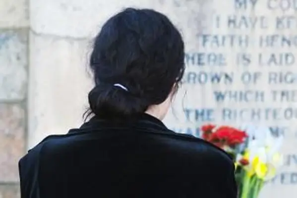 花と墓石による女性の背面図