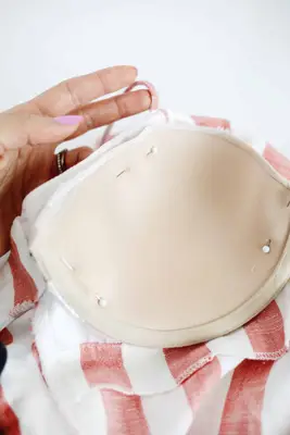 close up of one bra cup pinned into pink and white stripped dress