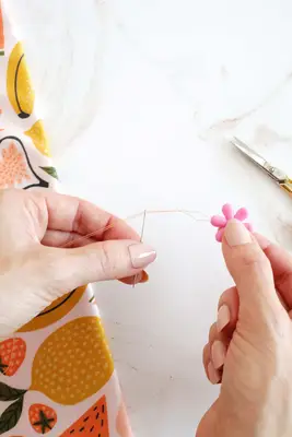 hand pulling a thread through a needle with a needle threader