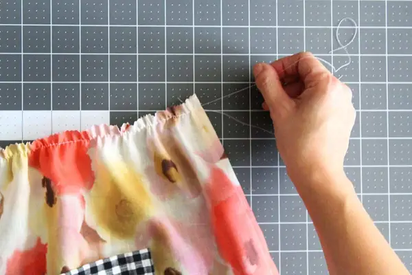 a white string being pulled through the hem of the flower fabric