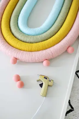 pink large felt balls being super glued onto the yarned wrapped pool noodles