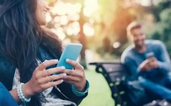 Coppia che flirta nel parco che manda sms su smartphone