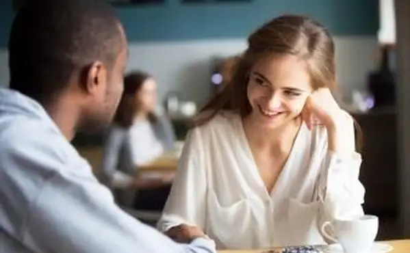Coppia che flirta parlando e tenendosi per mano in un bar