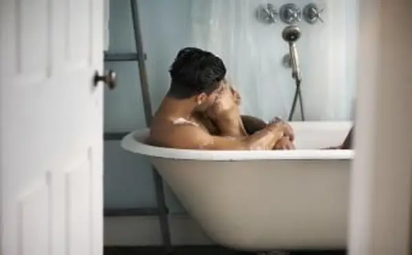 Giovane coppia che si bacia nella vasca da bagno a casa