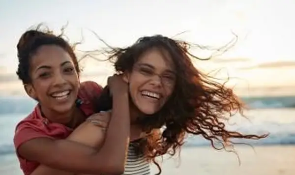 Las mujeres jóvenes a cuestas en la playa de arena