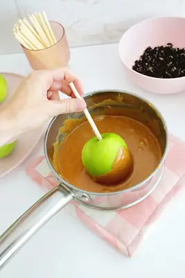 Dipping an apple on a stick into caramel
