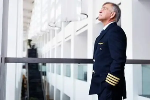 טייס בכיר ממתין בלובי שדה התעופה לטיסה