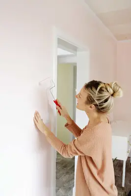 a blonde woman painting over the mudded hole in the wall