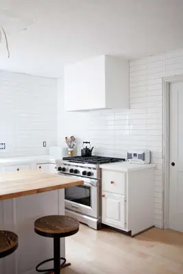 white modern hood vent cover over stainless stove in a white kitchen