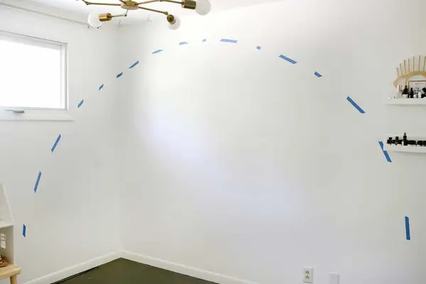 blue painters tape on wall to outline the rainbow