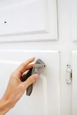 someone sanding the white cabinets where they took the gold knobs off