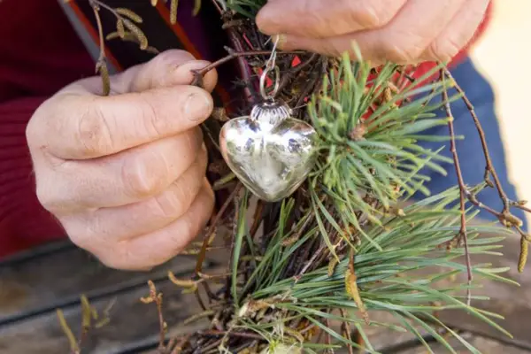Adding silver decorations to the wreath