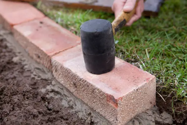 Edging a lawn - settling the bricks with a mallet