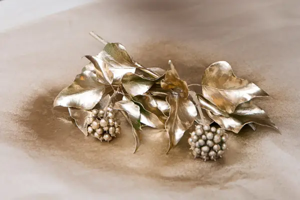 Spraying ivy sprigs with gold paint