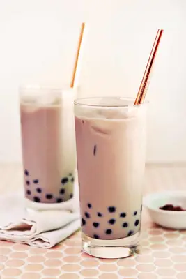 2 glasses og iced chair tea with boba pearls in it and a gold straw
