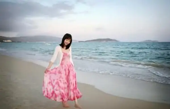 Ragazza che indossa un abito rosa e bianco che cammina sulla spiaggia