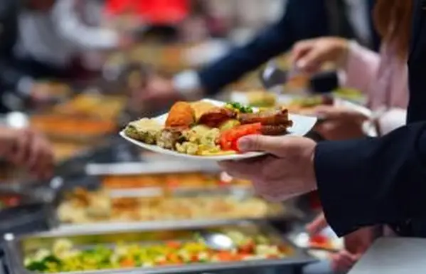 Les gens dans une ligne de buffet avec des assiettes pleines