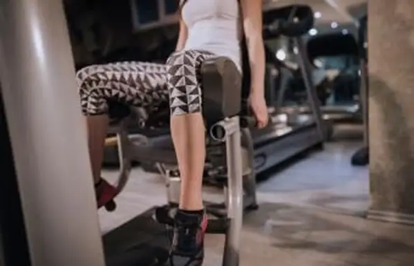 Mulher usando máquina de abdução de perna