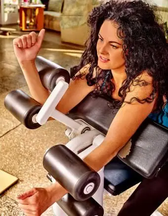 Mulher usando máquina de bíceps